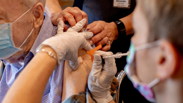 A health care worker administers a third dose of the Pfizer-BioNTech COVID-19 vaccine at a senior living facility in Worcester, Penn., in August.