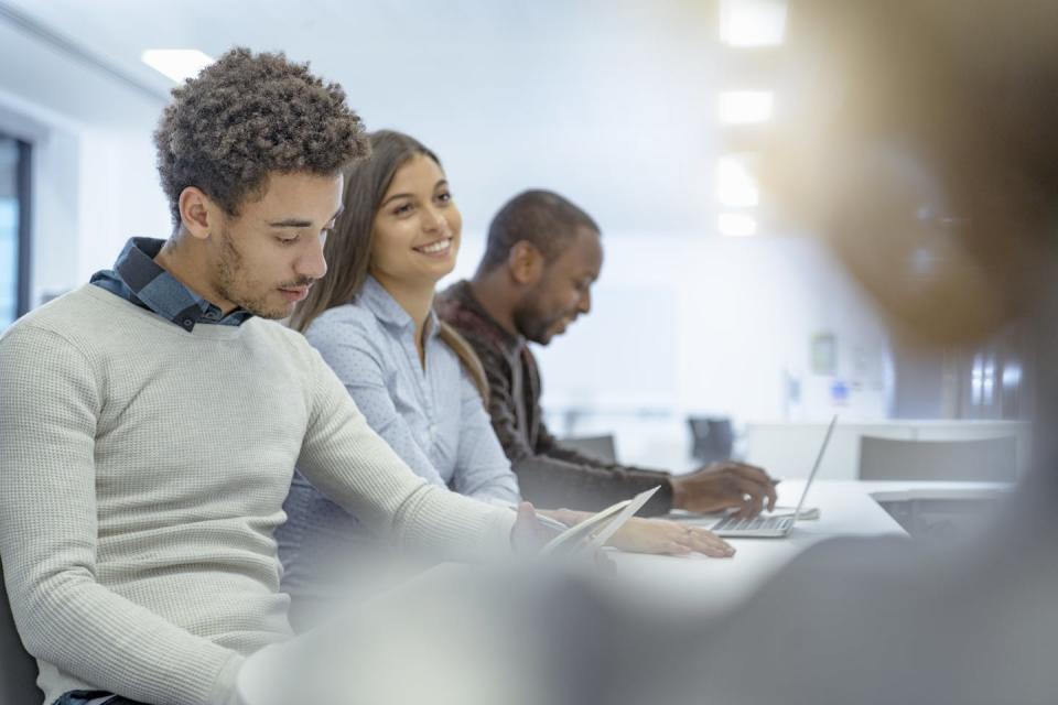 Three students work in a classroom.