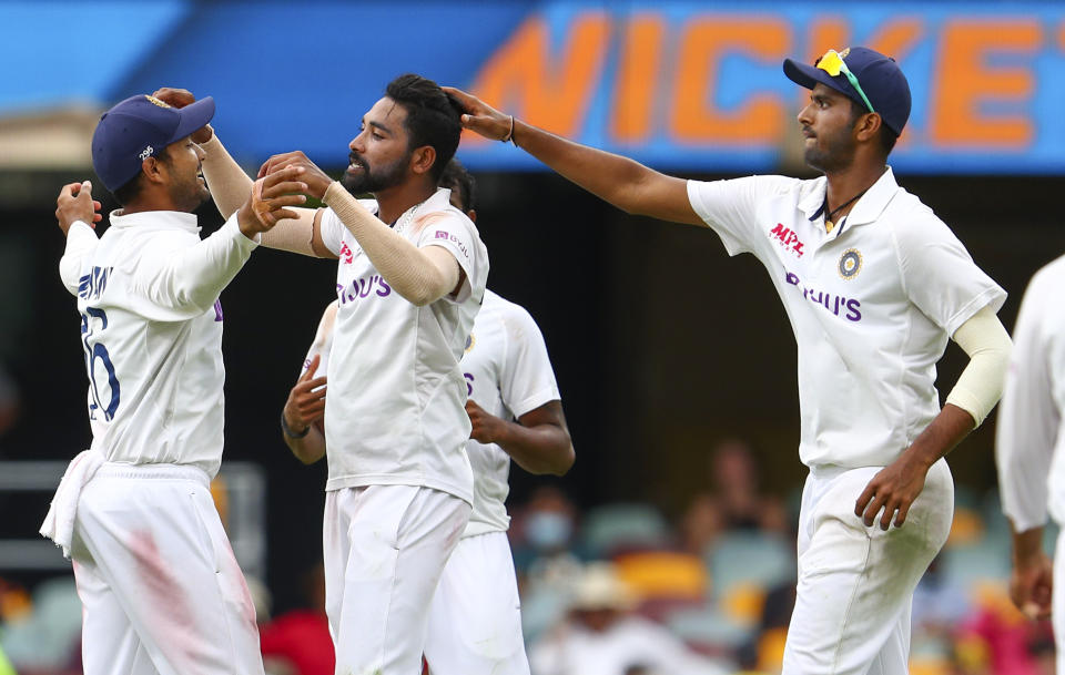 India's Mohammed Siraj, centre, celebrates with teammate Mayank Agarwal, left, after taking his fifth wicket during play on day four of the fourth cricket test between India and Australia at the Gabba, Brisbane, Australia, Monday, Jan. 18, 2021. (AP Photo/Tertius Pickard)