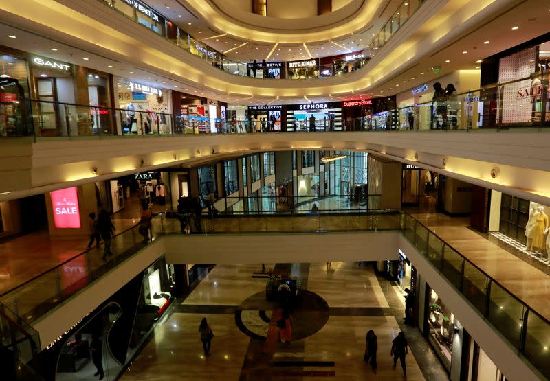 Shoppers walk past stores at a mall in Mumbai