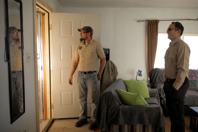 Kacey Dawson and Drew Miller stand inside the living room of a survival camp