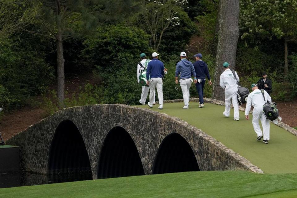 Tiger Woods, Tom Kim, Rory McIlroy and Fred Couples walk across the Ben Hogan Bridge during a practice round for The Masters golf tournament at Augusta National Golf Club.