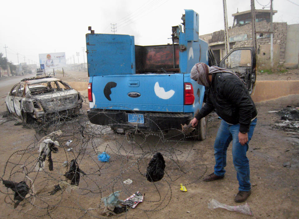 FILE - In this Friday, Jan. 10, 2014 file photo, a masked anti-government gunman clears debris after clashes in Fallujah, Iraq. Islamic militants who took over the Iraqi city of Fallujah are now trying to show they can run it, providing social services, policing the streets and implementing Shariah rulings in a bid to win the support of its Sunni Muslim population. (AP Photo, File)