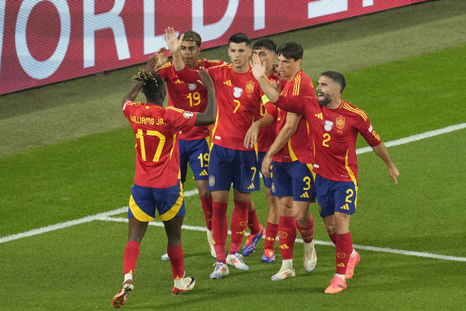 Spain's Alvaro Morata celebrates with teammates after Italy's Riccardo Calafiori, right, lies face down on the pitch after scoring an own goal during a Group B match between Spain and Italy at the Euro 2024 soccer tournament in Gelsenkirchen, Germany, Thursday, June 20, 2024. (AP Photo/Andreea Alexandru)