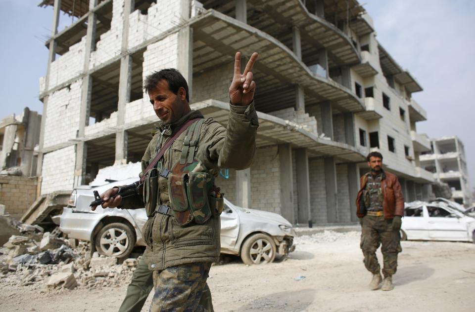 A fighter of the Kurdish People's Protection Units (YPG) flashes a V-sign as he patrols in the streets in the northern Syrian town of Kobani