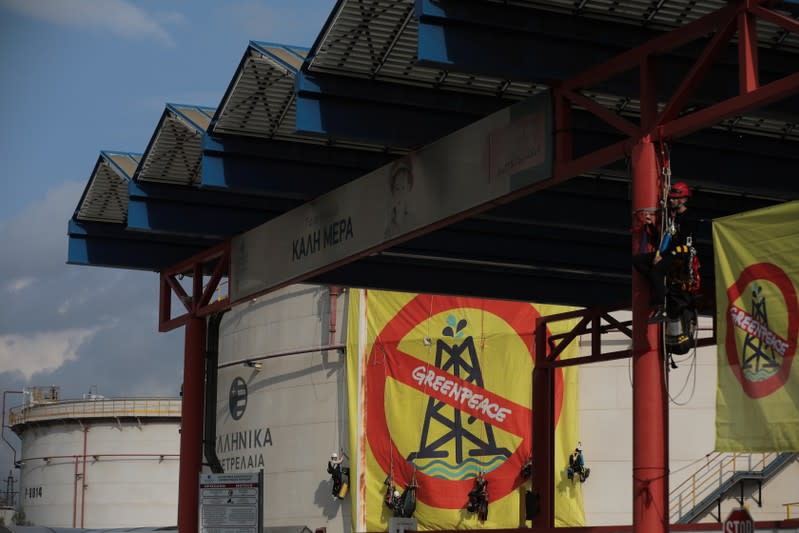 Greenpeace activists hang from an oil tank at the Hellenic Petroleum refineries in Aspropyrgos near Athens