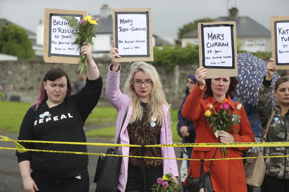 People hold up names of children as they gather to protest at the site of the former Tuam home for unmarried mothers in County Galway, during the visit to Ireland by Pope Francis, Sunday, Aug. 26, 2018. Survivors of one of Ireland's wretched mother and baby homes were to hold their own demonstration Sunday. The location is Tuam, site of a mass grave of hundreds of babies who died at a church-run home. (Niall Carson/PA via AP)