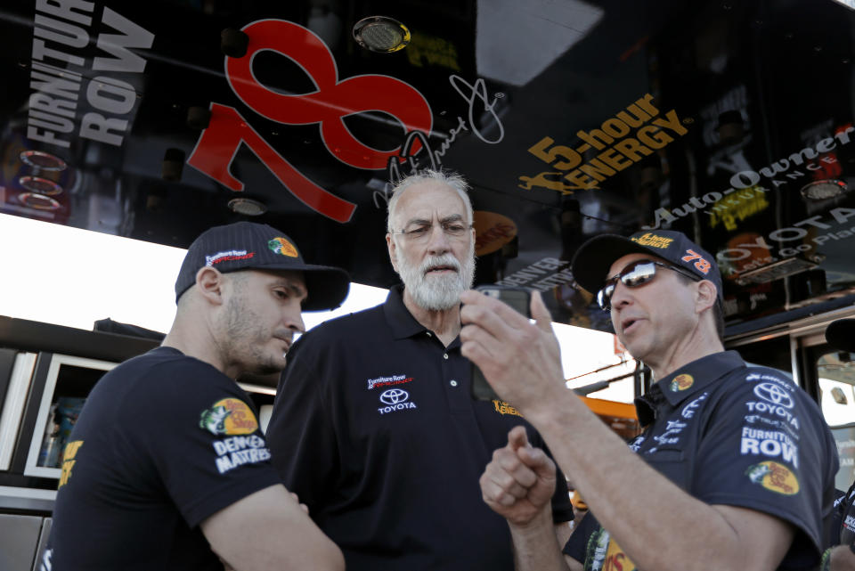 FILE - In this Feb. 15, 2018, file photo, Barney Visser, center, team owner of Furniture Row Racing, talks with crew members before the first of two qualifying races for the NASCAR Daytona 500 auto race at Daytona International Speedway in Daytona Beach, Fla. Furniture Row Racing will cease operations at the end of this season, shutting its doors one year after Martin Truex Jr. won NASCAR’s championship driving for the maverick race team. Furniture Row is an anomaly in NASCAR in that it is a single-car team based in Denver, Colorado, far removed from the North Carolina hub. Team owner Barney Visser was a racing enthusiast with a vision when he launched the team in 2005 determined to do it his own way. But a lack of sponsorship for next season led Visser to make the “painful decision” to close the team. (AP Photo/Chuck Burton, File)