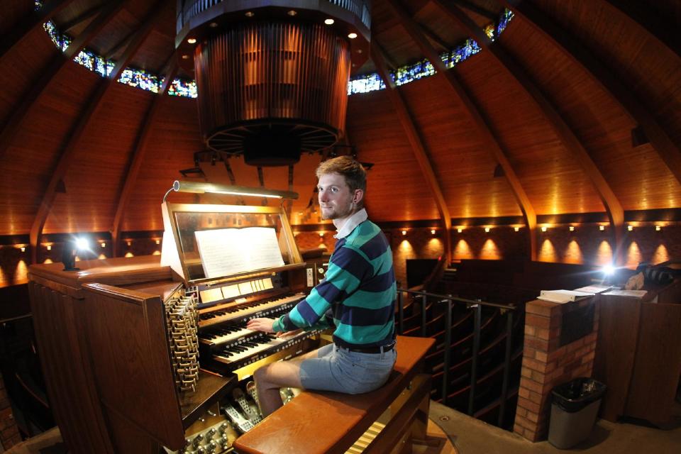 Organist Christopher Keady sits at the circular pipe organ at the Agnes Flanagan Chapel Tuesday, June 12, 2012, on the campus of Lewis & Clark College, in Portland, Ore. The Agnes Flanagan Chapel is a 16-sided architectural marvel that seats 650 under stained glass windows depicting the book of Genesis. In the early 1970s, it was also a big, conical quandary. Chapels aren’t really chapels unless they have an organ, and the newly-minted structure at Portland’s Lewis & Clark College was in need. (AP Photo/Rick Bowmer)