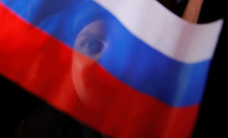 A man waves Russian flag during a rally and concert marking the fourth anniversary of Russia's annexation of the Crimea region, at Manezhnaya Square in central Moscow, Russia March 18, 2018. REUTERS/Maxim Shemetov