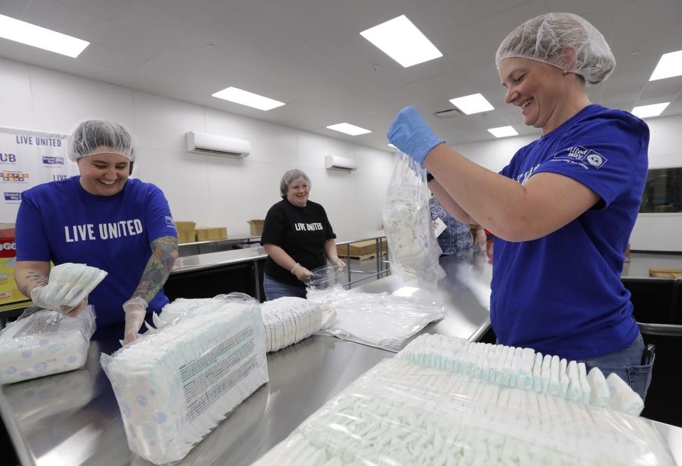 (From left) Theresa Cross of Appleton, Nicolle Lorbiecki of Menasha and Trace Fahrenkrug of New London collaborate to repackage donated diapers for the Kimberly-Clark Diaper Bank at the United Way Fox Cities Hub at VPI Inc. in Appleton.