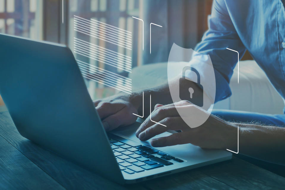 A man sits at a laptop. A stylised padlock floats above the keyboard. (Source: Getty)