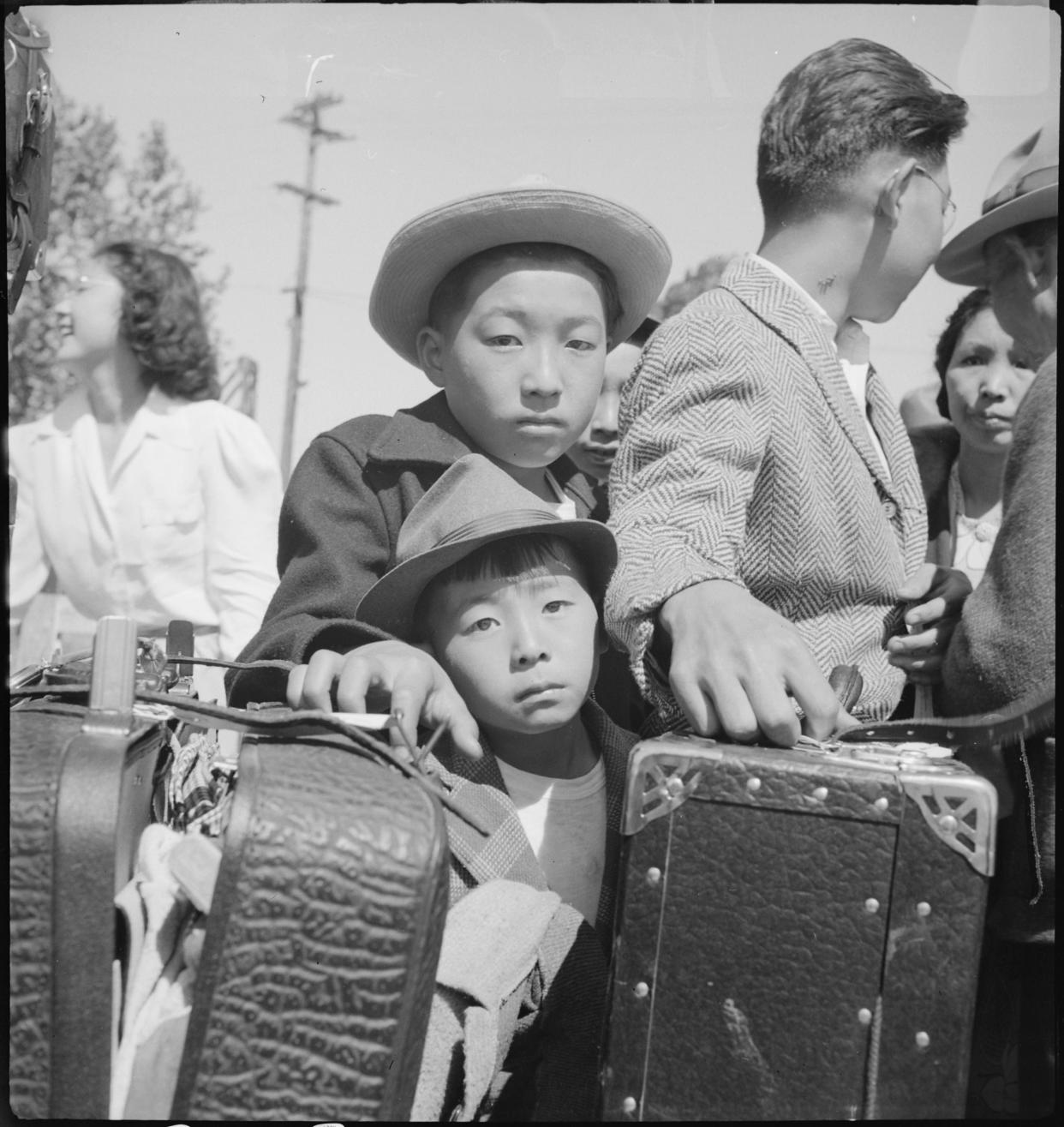 Two children waiting with luggage to be removed to Japanese internment camps