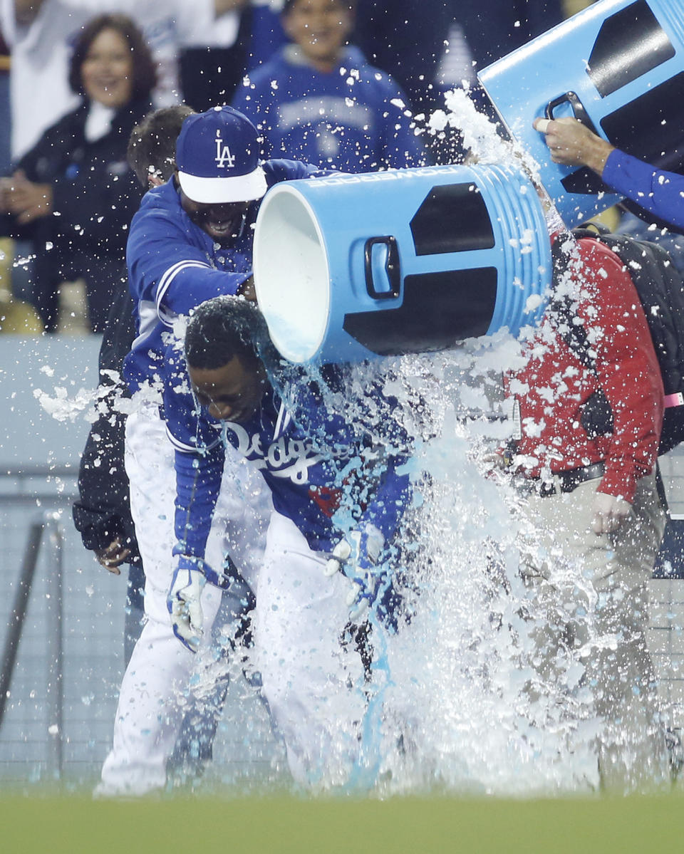 Los Angeles Dodgers' Darnell Sweeney is doused by teammates including Chone Figgins, left, after hitting a walk off single to score Trayvon Robinson against the Los Angeles Angels during the 10th inning of an exhibition baseball game in Los Angeles, Friday, March 28, 2014. The Dodgers won 5-4. (AP Photo/Danny Moloshok)