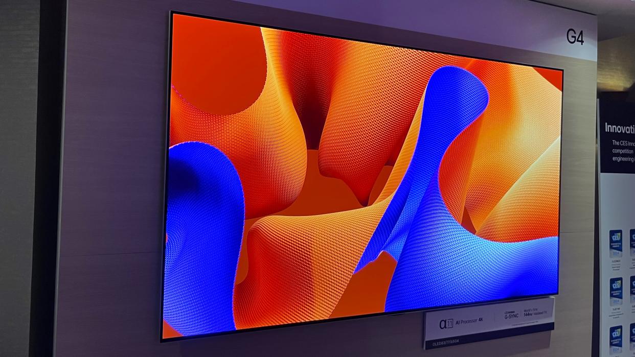  LG G4 OLED TV mounted on wall displaying an abstract blue and orange image. 