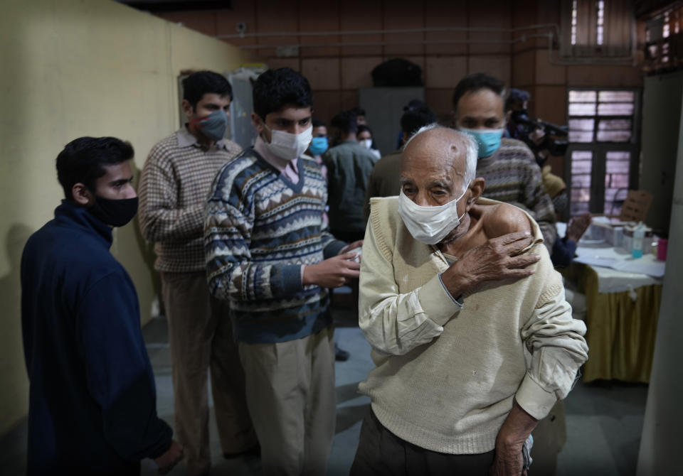 An elderly man leaves after getting Covid-19 vaccination at a makeshift center in a government school in New Delhi, India, Friday, Jan. 28, 2022. Indian health officials said that the first signs of COVID-19 infections plateauing in some parts of the vast country were being seen, but cautioned that cases were still surging in some states. (AP Photo/Manish Swarup)