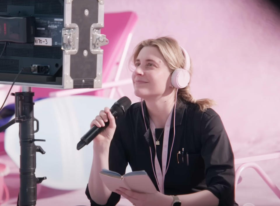 Greta Gerwig looking at a monitor as she directs Barbie