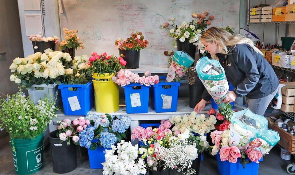 Jill Landry, owner of Beach Plum Floral in Marshfield, works on wedding floral arraignments in her workshop on Monday, May 2, 2022.