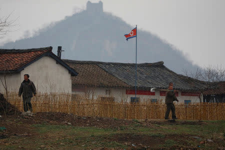 North Korean people walk in a field as a section of the Great Wall is seen on the Chinese side of the Yalu River, north of the town of Sinuiju in North Korea and Dandong in China's Liaoning province, April 14, 2017. REUTERS/Aly Song