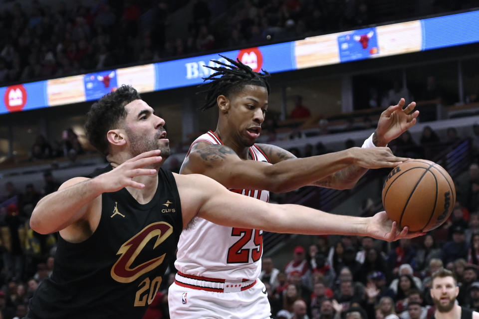 Cleveland Cavaliers forward Georges Niang (20) and Chicago Bulls forward Dalen Terry (25) reach for the ball during the first half of an NBA basketball game Saturday, Dec. 23, 2023, in Chicago. (AP Photo/Matt Marton)