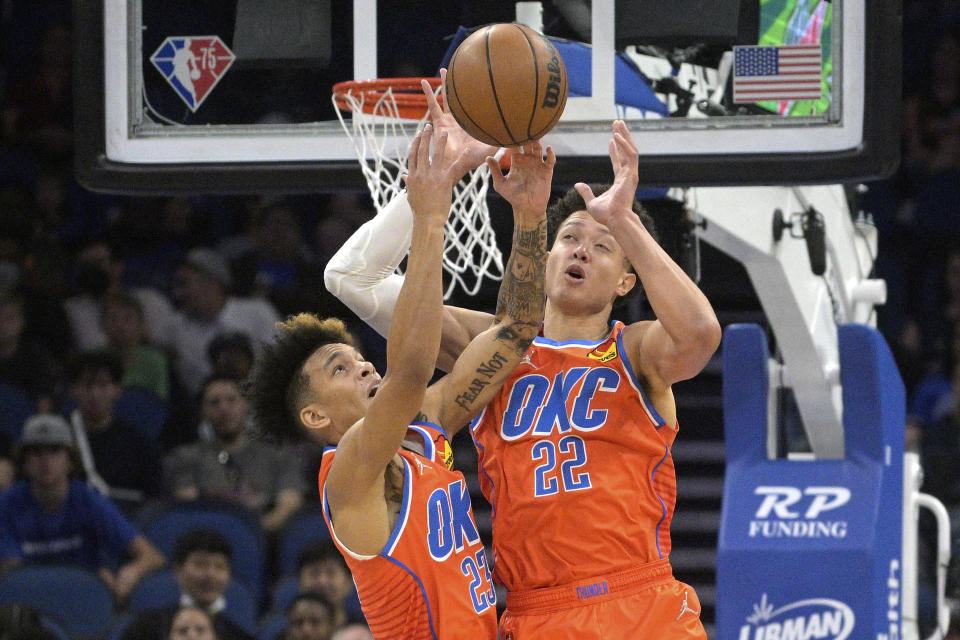 Oklahoma City Thunder guard Tre Mann (23) and forward Isaiah Roby (22) go for a rebound during the first half of an NBA basketball game against the Orlando Magic, Sunday, March 20, 2022, in Orlando, Fla. (AP Photo/Phelan M. Ebenhack)