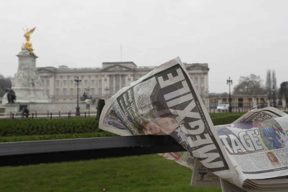 A newspaper is blown by the wind after it is placed on a railing by a television crew outside Buckingham Palace in London, Monday, March 8, 2021. Britain's royal family is absorbing the tremors from a sensational television interview by Prince Harry and the Duchess of Sussex, in which the couple said they encountered racist attitudes and a lack of support that drove Meghan to thoughts of suicide. (AP Photo/Kirsty Wigglesworth)