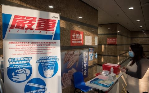 A woman walks past signs during a media tour at a designated treatment clinic for coronavirus, known as 2019-nCoV, in the Kowloon Bay district of Hong Kong - Credit: Paul Yeung/Bloomberg