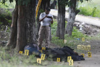 Un policía de la Fiscalía General toma fotografías de los cuerpos de policías asesinados en El Papayo, municipio de Coyuca de Benítez, estado de Guerrero, México, el lunes 23 de octubre de 2023. (AP Foto/Bernardino Hernández)