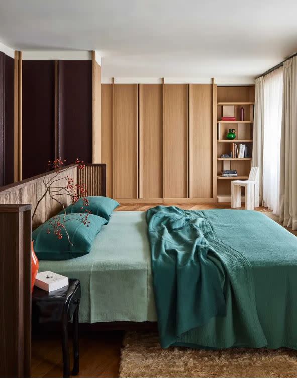 bedroom with green bedding and wood  wardrobes