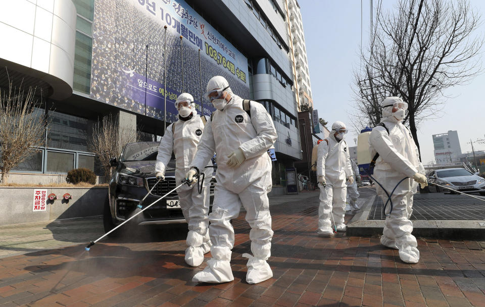 Image: Workers wearing protective gears spray disinfectant against the new coronavirus in front of a church in Daegu, South Korea,