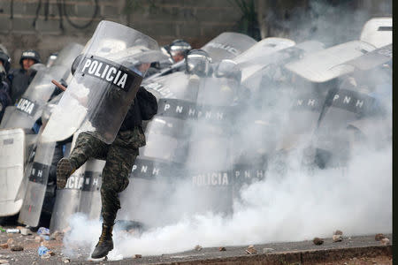 A soldier kicks a tear gas canister during a clash with supporters of Salvador Nasralla, presidential candidate for the Opposition Alliance Against the Dictatorship, as they wait for official presidential election results in Tegucigalpa, Honduras, November 30, 2017. REUTERS/Edgard Garrido