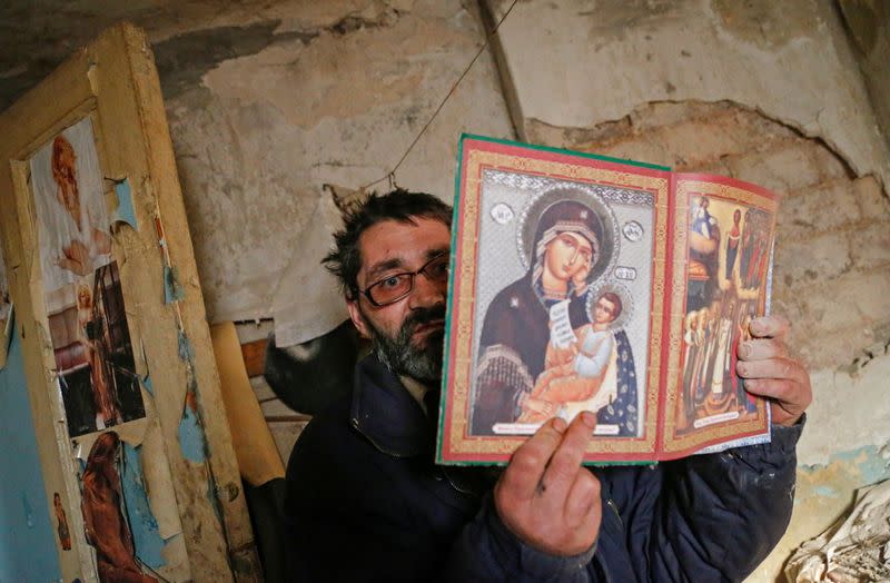 Local resident Aleksander Studenikin shows Orthodox icons inside his house, which was damaged by shelling, in Horlivka