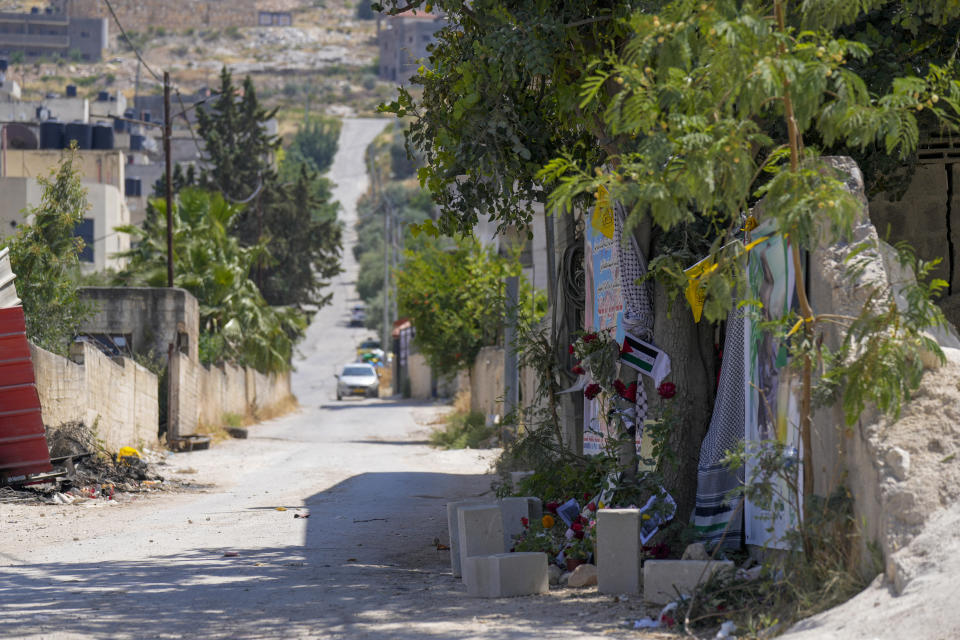 Flowers, flags and other memorabilia create a makeshift memorial at the site where veteran Palestinian-American reporter Shireen Abu Akleh was shot and killed, in the West Bank city of Jenin, May 19, 2022. Almost two weeks after the death of Abu Akleh, a reconstruction by The Associated Press lends support to assertions from both Palestinian authorities and Abu Akleh's colleagues that the bullet that cut her down came from an Israeli gun. (AP Photo/Majdi Mohammed)