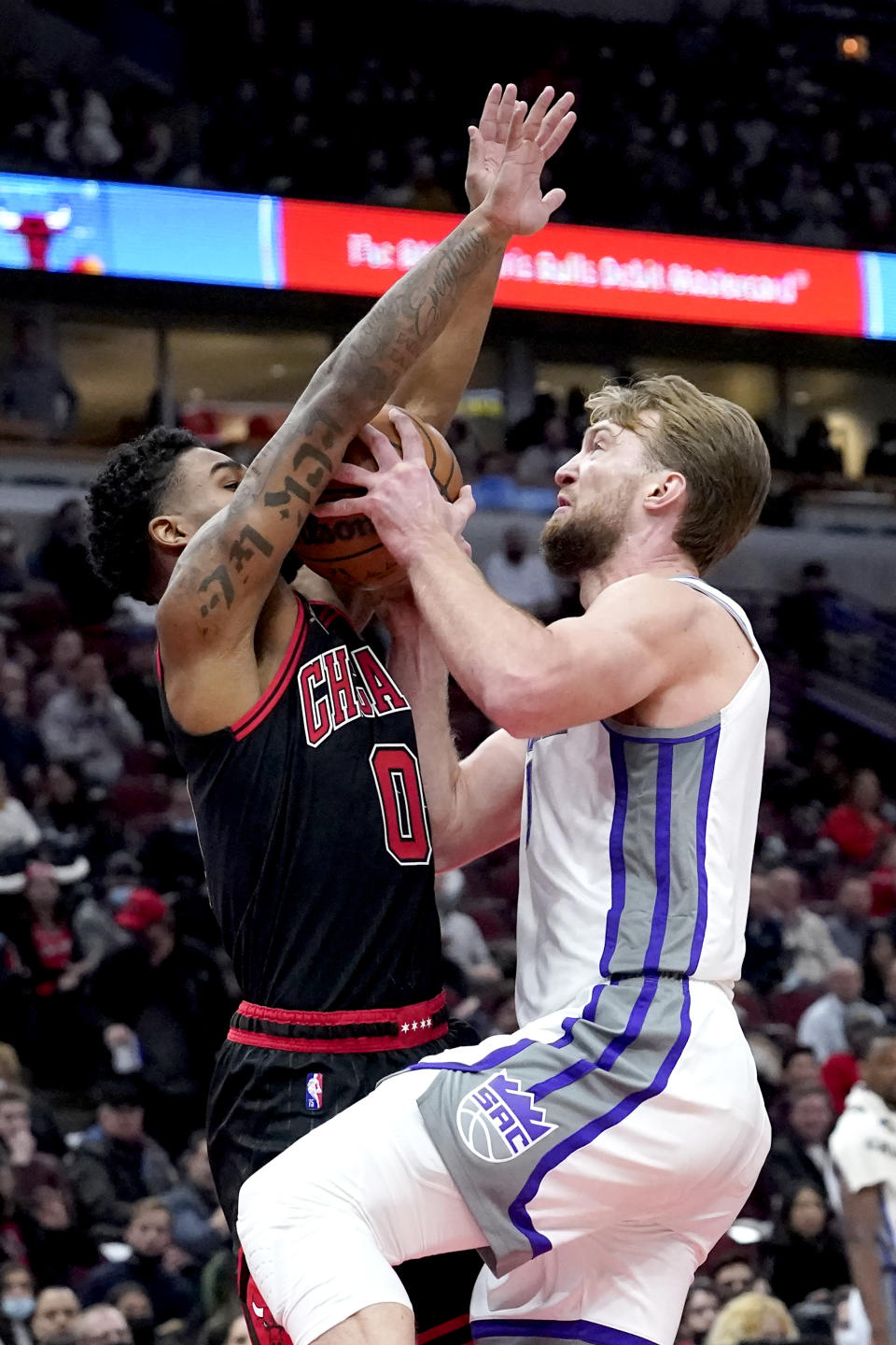 Chicago Bulls' Coby White (0) fouls Sacramento Kings' Domantas Sabonis during the first half of an NBA basketball game Wednesday, Feb. 16, 2022, in Chicago. (AP Photo/Charles Rex Arbogast)