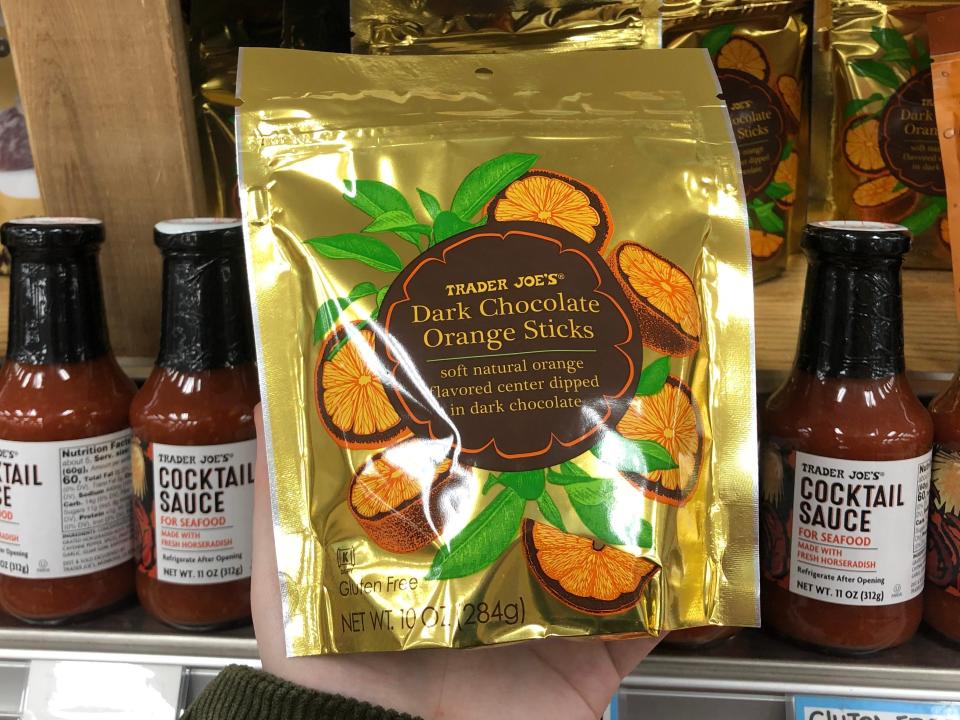 A hand holding a bag of Trader Joe's dark-chocolate orange sticks. 