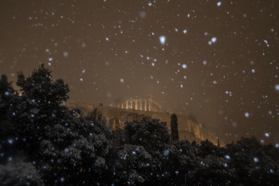 The ancient Parthenon temple on the Acropolis hill is illuminated during a snowfall in central Athens , early Tuesday, Feb. 16, 2021. A cold weather front has hit Greece, sending temperatures plunging from the low 20s degrees Celsius (around 70 Fahrenheit) on Friday to well below freezing on Monday, and seeing snowfall in central Athens. (AP Photo/Petros Giannakouris)