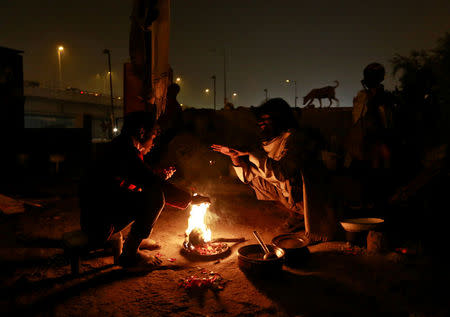 People warm themselves by a fire to escape the cold in Delhi, India January 16, 2017. REUTERS/Cathal McNaughton