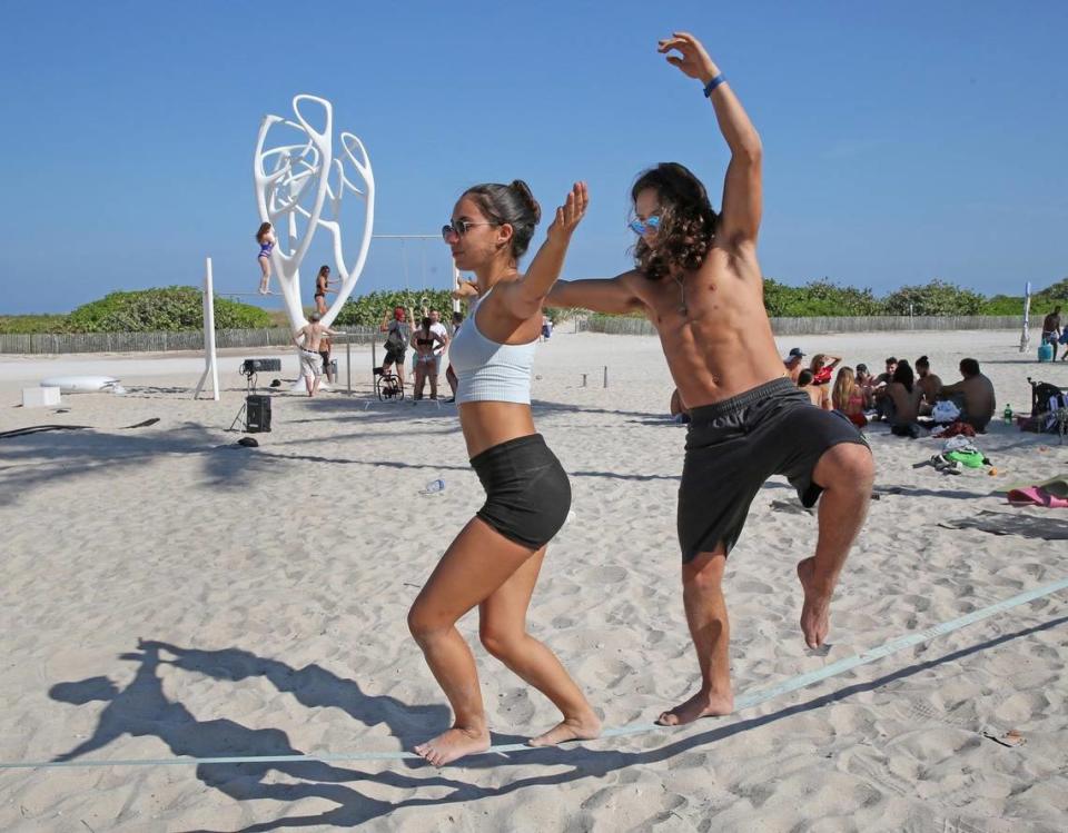 Ishani Falconi and Rodolfo Rojas keep their balance on a tandem slack line on Ocean Drive and Eighth street as spring breakers and locals take over South Beach on Tuesday, March 20, 2018