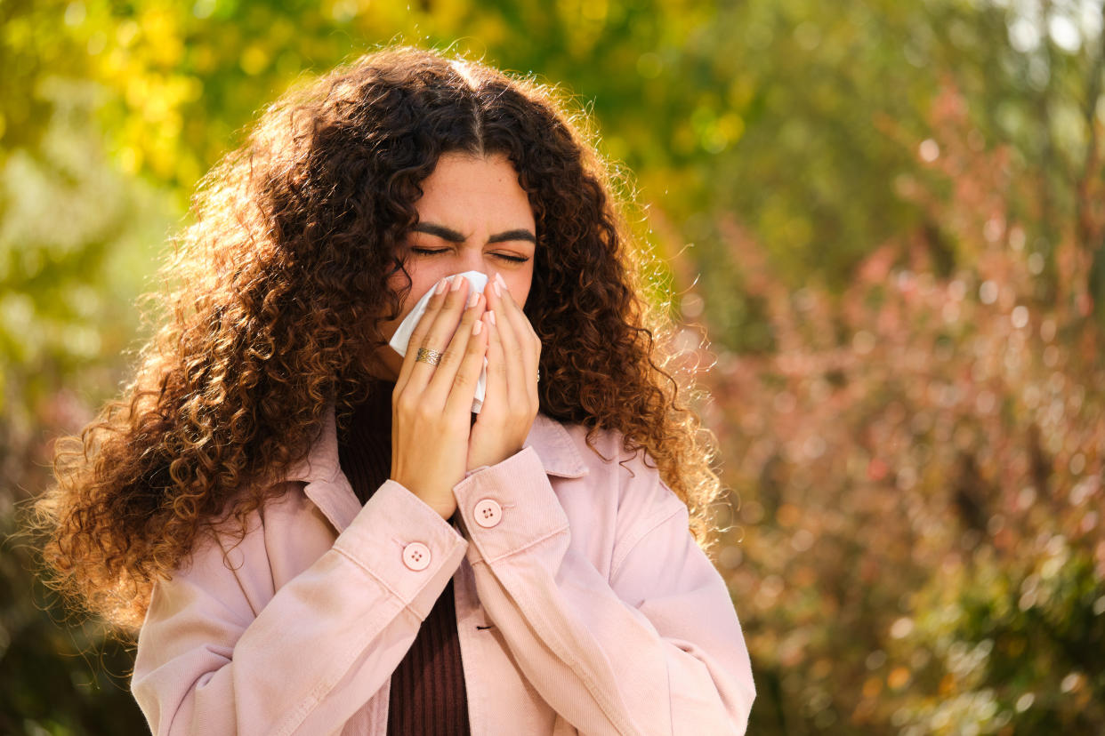 A woman sneezing due to allergies