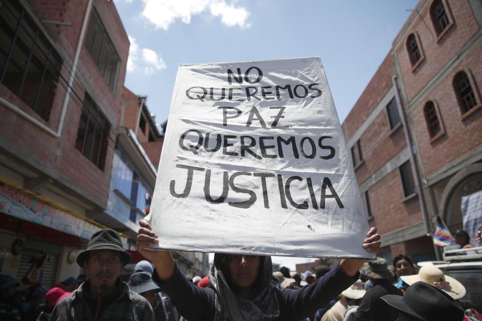 A supporter of former President Evo Morales holds a sign with a handwritten message that reads in Spanish: "We don't want peace, We want justice," during a protest at a blocked highway in El Alto, on the outskirts of La Paz, Bolivia, Wednesday, Nov. 20, 2019. Bolivia has been in a state of turbulence since a disputed Oct. 20 vote. Morales resigned Nov. 10, but his supporters oppose the interim government that took his place. (AP Photo/Natacha Pisarenko)