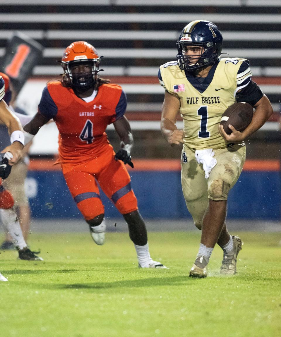 Gulf Breeze running back Troy Coughlin (No. 1) slips past the Escambia defense for a few extra yards during Friday night's rain soaks game.