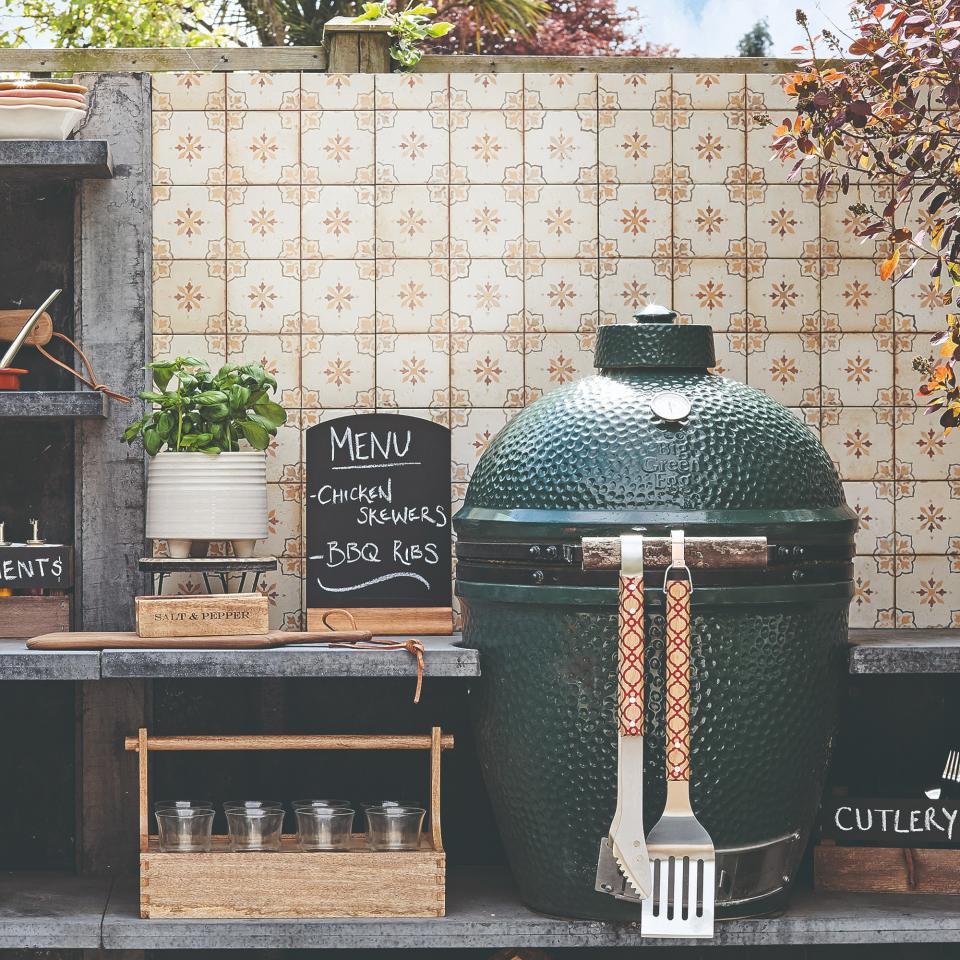 An outdoor kitchen with a BBQ and a basil plant