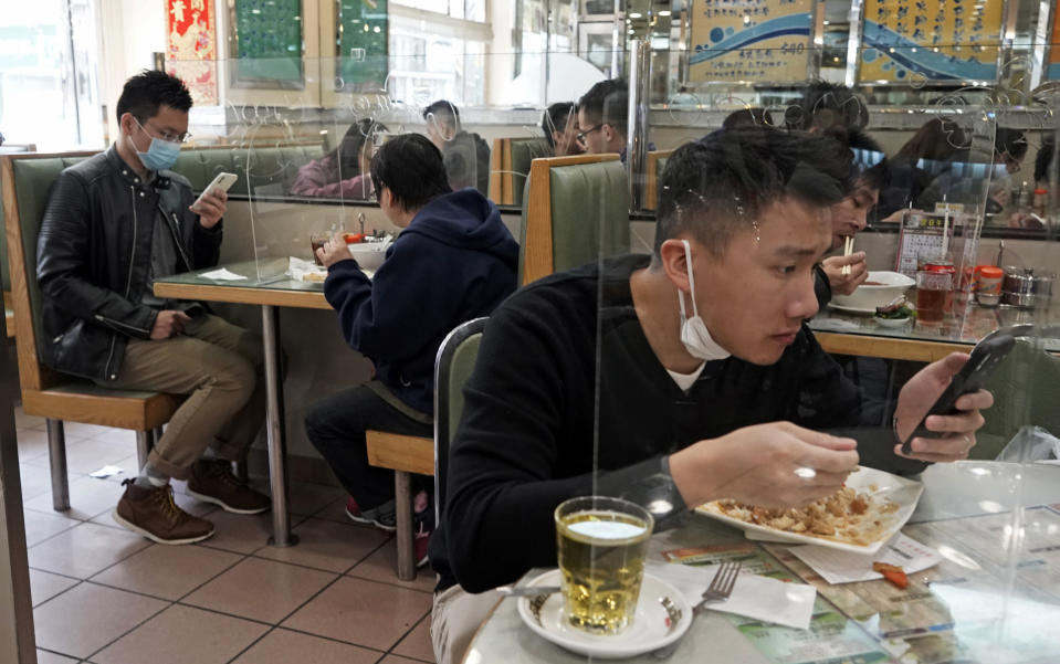 Customers have lunch with a transparent plastic panel setup on the table to isolate each others to prevent virus spreading in Hong Kong, Feb. 12, 2020. (AP Photo/Kin Cheung)