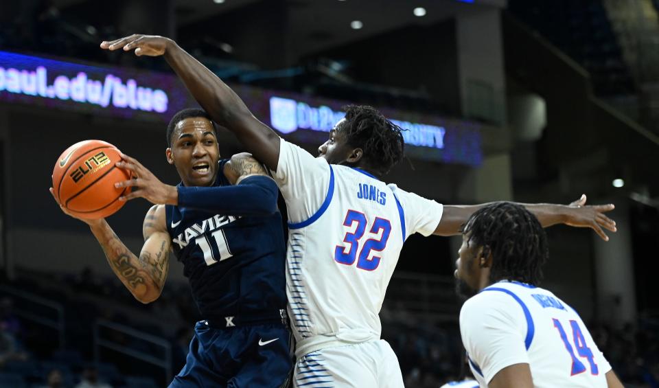 Jan 19, 2022; Chicago, Illinois, USA;  Xavier Musketeers guard Dwon Odom (11) passes past DePaul Blue Demons forward David Jones (32) and center Nick Ongenda (14) during the first half at Wintrust Arena.