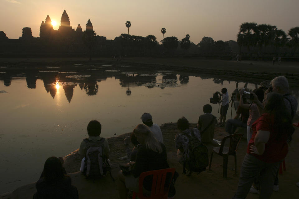 In this March 30, 2008 photo, tourists watch the sunrise at the famed Angkor Wat temple in Siem Reap province, Cambodia. Cambodia has joined hands with Australia in an effort to use the Internet to help preserve its fabled Angkor Wat temple complex. The Australian Embassy announced Thursday, July 4, 2013, that a recently-opened website, angkorsunsets.com, will allow tourists to generate recommendations for where in the 160-square-mile (400-square-kilometer) complex one can watch spectacular sunsets. (AP Photo/Heng Sinith)