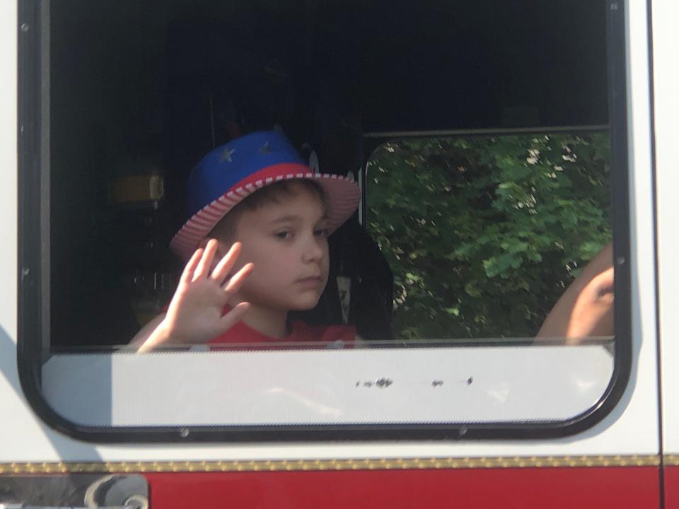 A youngster waves from a fire truck during a Memorial Day parade in the City of Hornell on May 29, 2023.