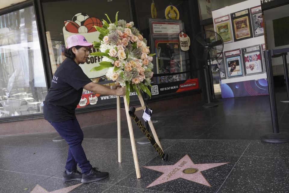 A staff member places flowers on Clarence Avant's star on the Hollywood Walk of Fame
