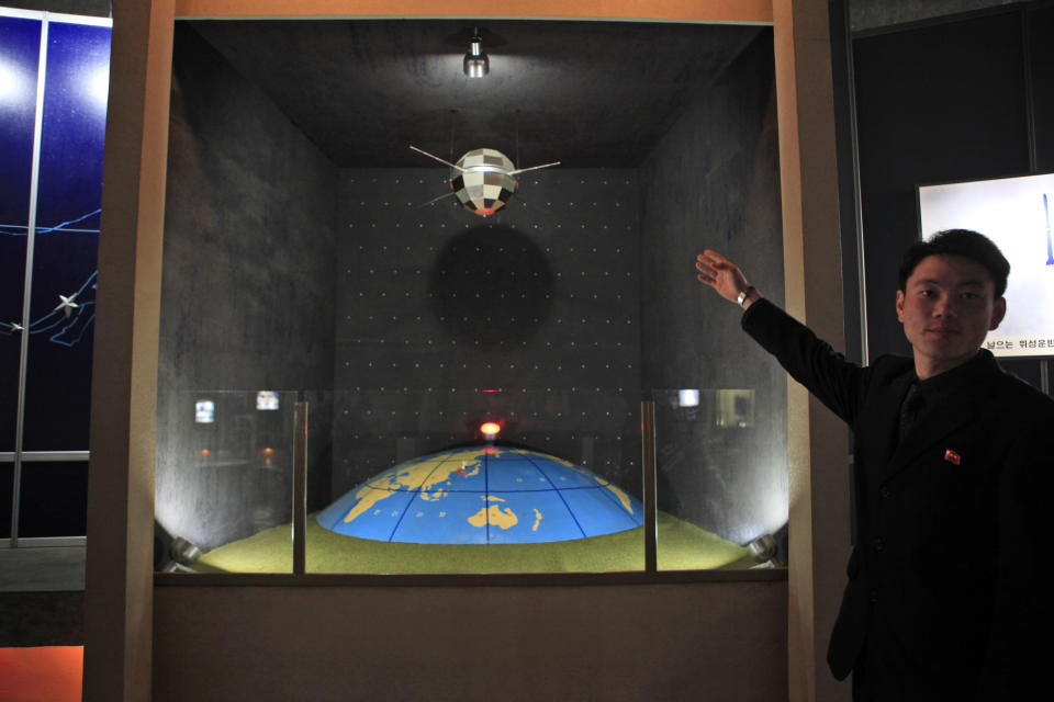 FILE - In this file photo taken Tuesday, April 10, 2012, North Korean guide Kim Won Ho shows journalists a model depicting a North Korean satellite over planet earth at the Three Revolutions exhibition hall in Pyongyang, North Korea. According to North Korea's official version of things, commemorated on postage stamps and re-enacted in mass performances, the country's first venture into space was 14 years ago, when the "Bright Shining Star 1" satellite roared into orbit and began broadcasting marching music praising Kim Il Sung. (AP Photo/Ng Han Guan, File)