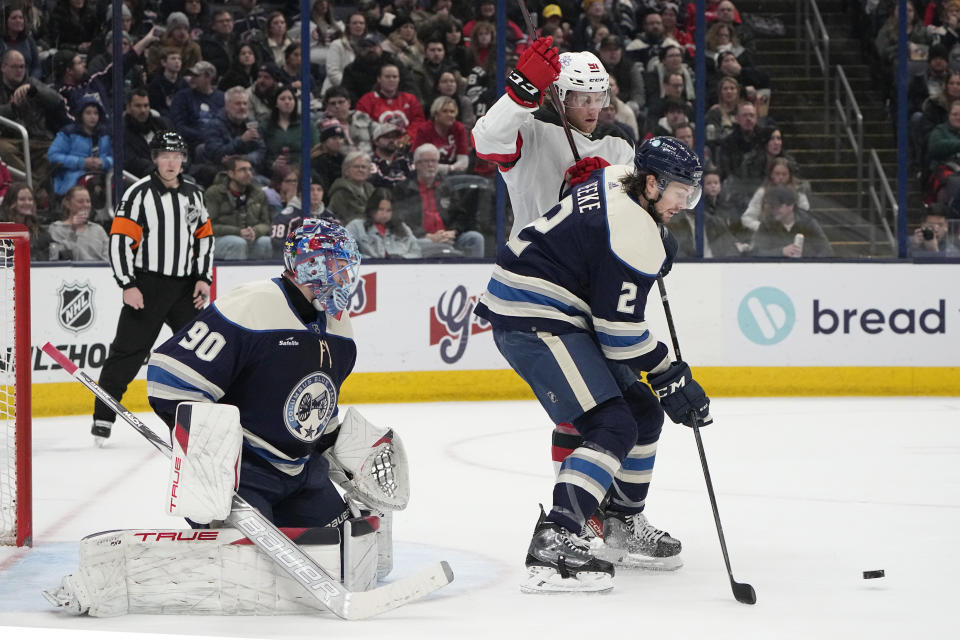 Columbus Blue Jackets defenseman Andrew Peeke (2) keeps New Jersey Devils center Dawson Mercer (91) away from the puck in front of Blue Jackets goaltender Elvis Merzlikins during the first period of an NHL hockey game Friday, Jan. 19, 2024, in Columbus, Ohio. (AP Photo/Sue Ogrocki)