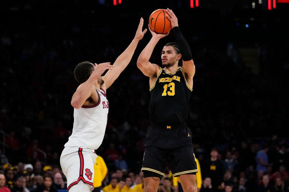 Michigan's Olivier Nkamhoua (13) shoots over St. John's Chris Ledlum, left, during the first half of an NCAA college basketball game Monday, Nov. 13, 2023, in New York. (AP Photo/Frank Franklin II)